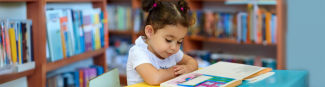 Young child reading a book in pre-k class