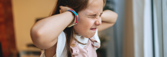 Child trying to block her ears.