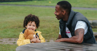 Father and child sitting at a picnic table in a park